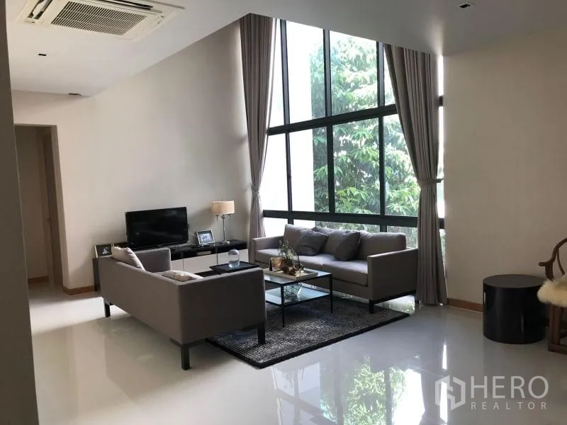 บ้าน ให้เช่าหรือขายในHuai Khwang, Bangkok - มุมนั่งเล่นสว่าง โปร่ง กระจกบานใหญ่ โซฟาคู่ ผ้าม่านสูง และพื้นเงางาม
