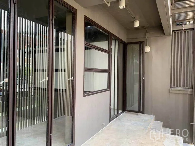 Home Office for rent in Huai Khwang, Bangkok - Outdoor balcony walkway with sliding glass doors and louvered panels.