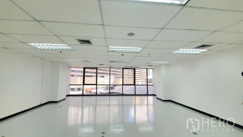 办公空间 出租在Watthana, Bangkok - 明亮的开放式办公区，亮面地坪、格栅天花灯，整面大窗享城市景观。