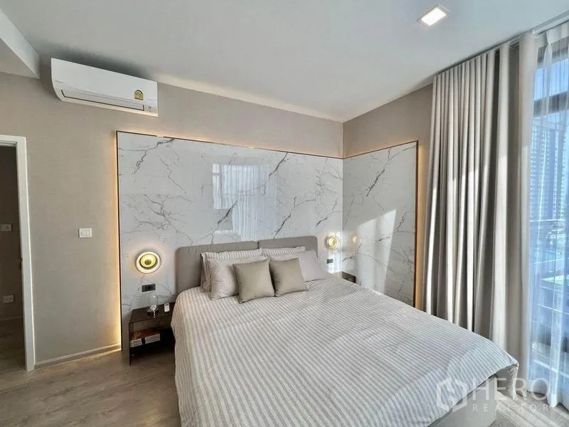 Condominium for rent in Watthana, Bangkok - Cozy bedroom featuring marble paneling, bedside lighting and large window with curtains.