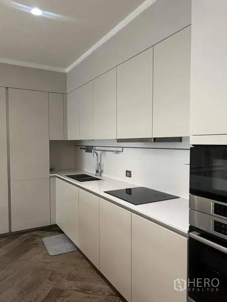 Condominium for sale - Sleek galley kitchen with white cabinetry, induction cooktop, and built-in ovens.