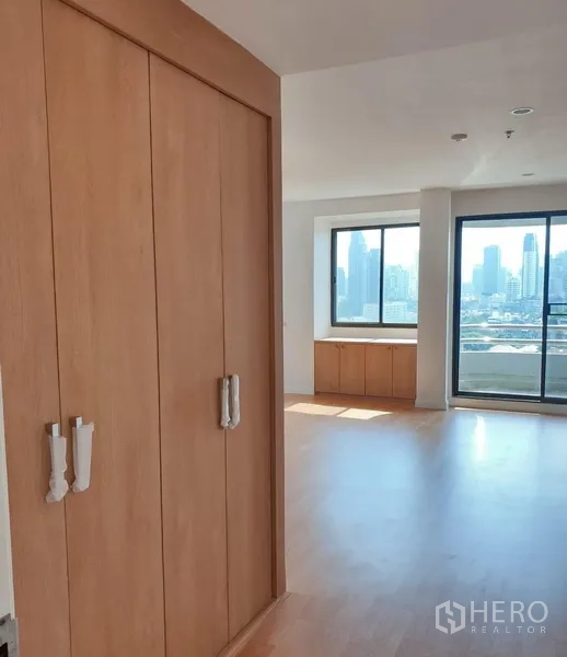 Condominium for rent in Watthana, Bangkok - Hallway with built-in closet opening to a bright living area with city skyline views.