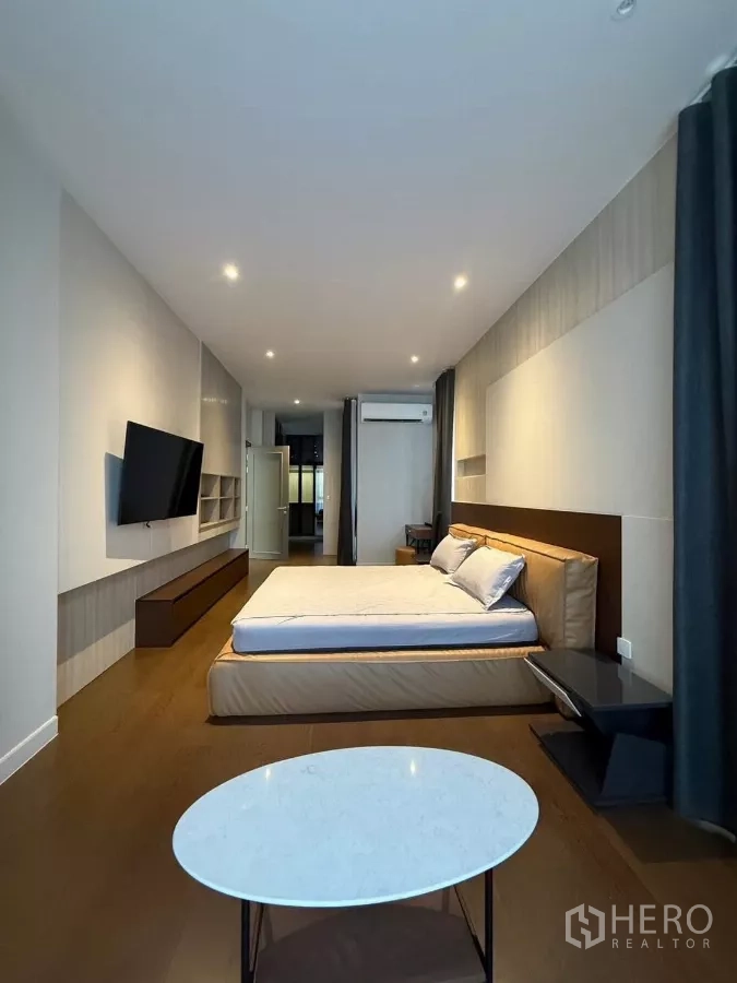 Detached House for rent in Saphan Sung, Bangkok - Cozy bedroom with wood flooring, wall-mounted TV and large windows with curtains.