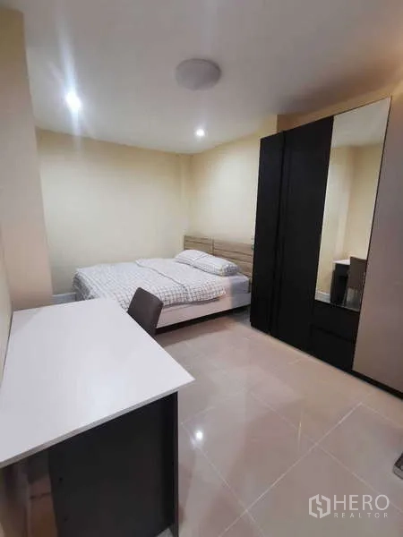 Townhouse for rent in Chatuchak, Bangkok - Guest bedroom with desk, black wardrobe and tile flooring.