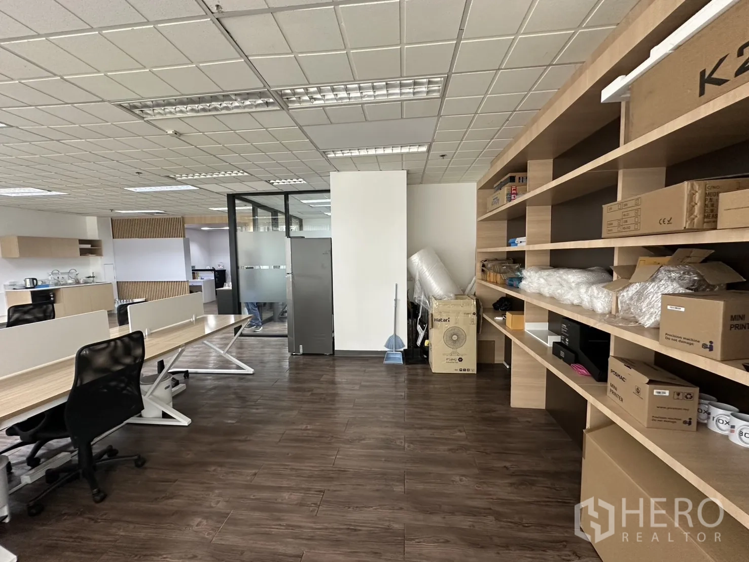 Office Space for rent - Wall-length built-in shelving for organized storage next to desks on wood flooring.