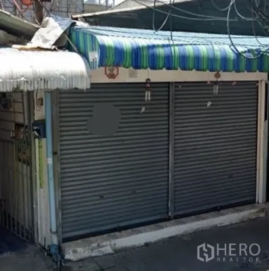 Retail Space for rent in Watthana, Bangkok - Streetfront retail exterior with double metal roller shutters and striped awning on a narrow lane.