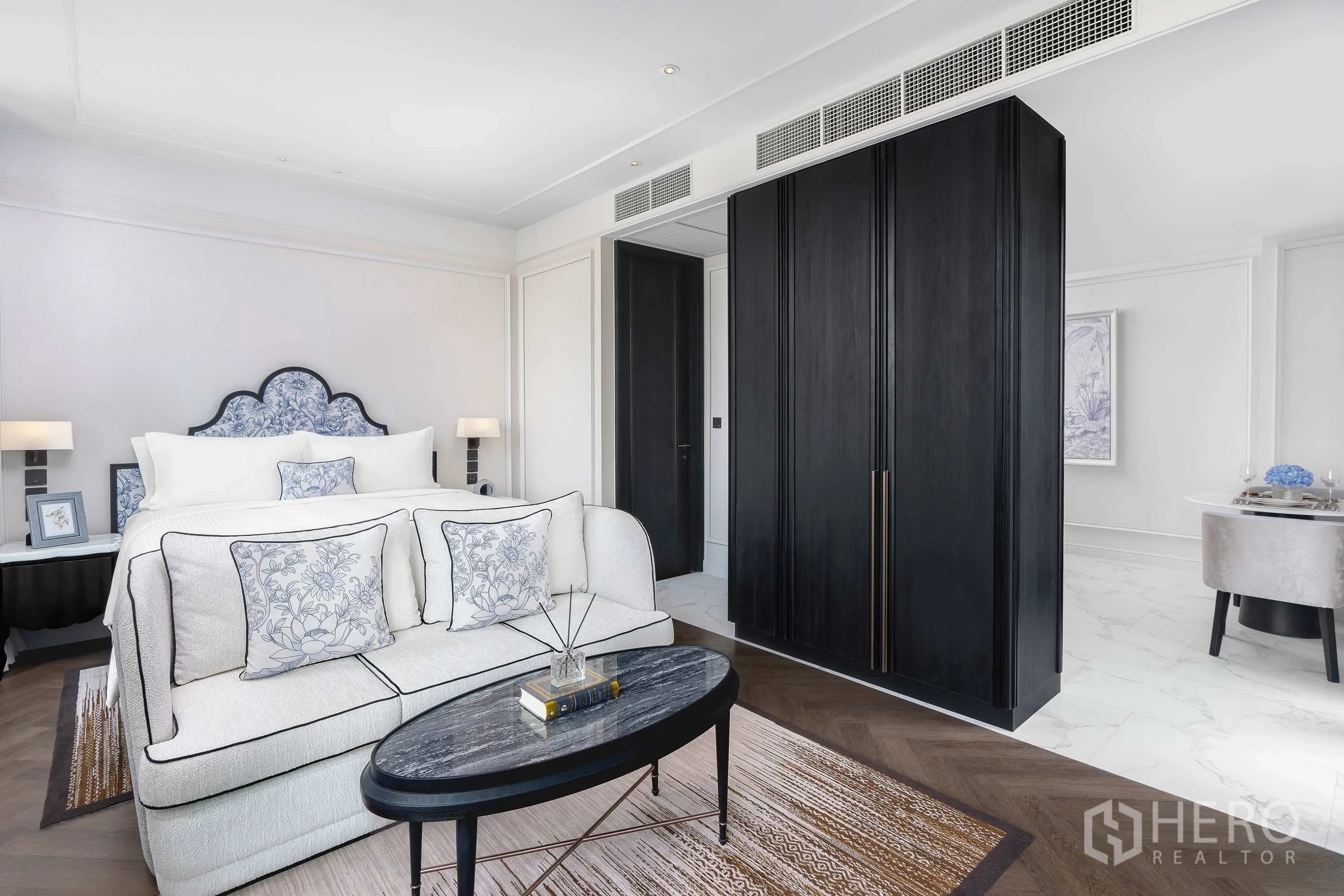 คอนโด for rent in Khlong Toei, Bangkok - โซฟาและโต๊ะกาแฟปลายเตียง พร้อมตู้เสื้อผ้าสูงและพื้นไม้ลายก้างปลา