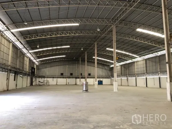 Factory for rent in Phra Nakhon Si Ayutthaya - Spacious empty warehouse interior with high arched steel roof, concrete floor, and skylight panels.