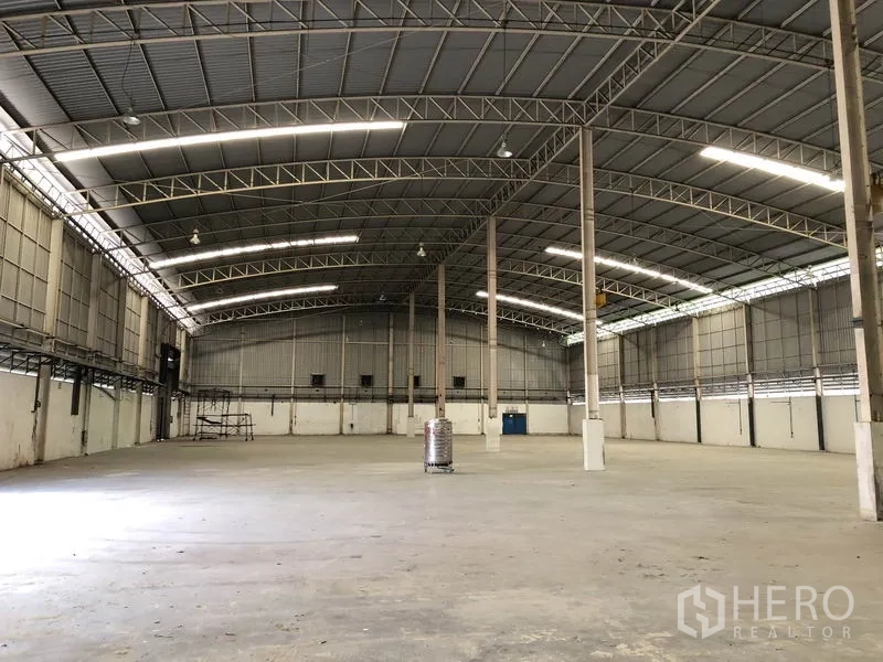 Factory for rent in Phra Nakhon Si Ayutthaya - Spacious empty warehouse interior with high arched steel roof, concrete floor, and skylight panels.