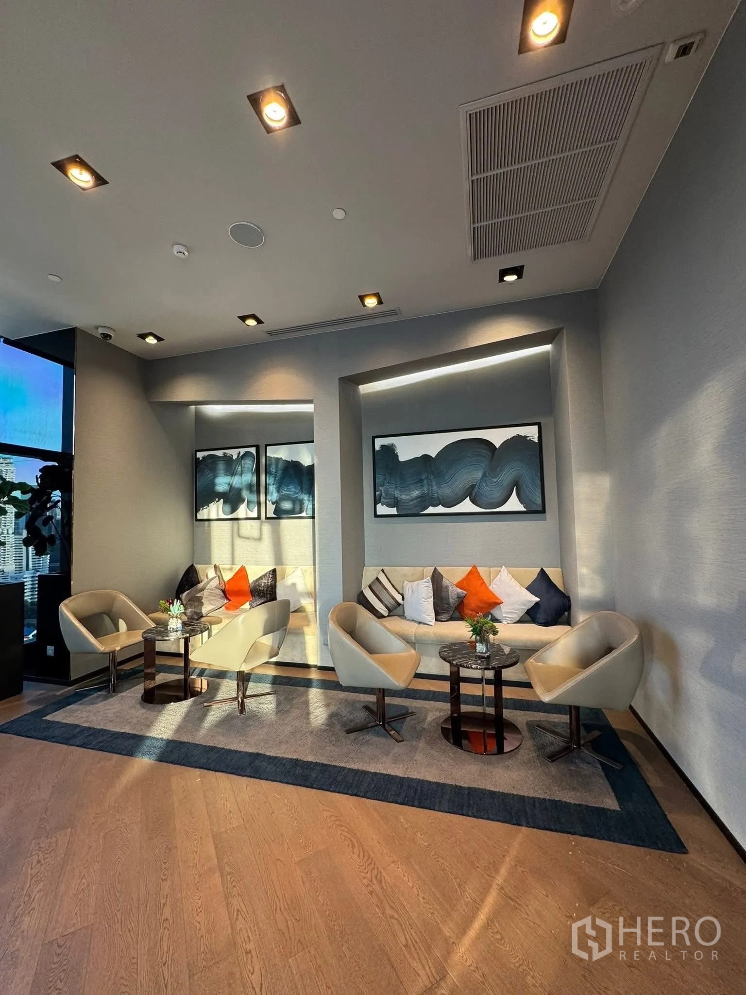 Condominium for rent in Khlong Toei, Bangkok - Bright residents’ lounge with modern armchairs, sofa and wall art.