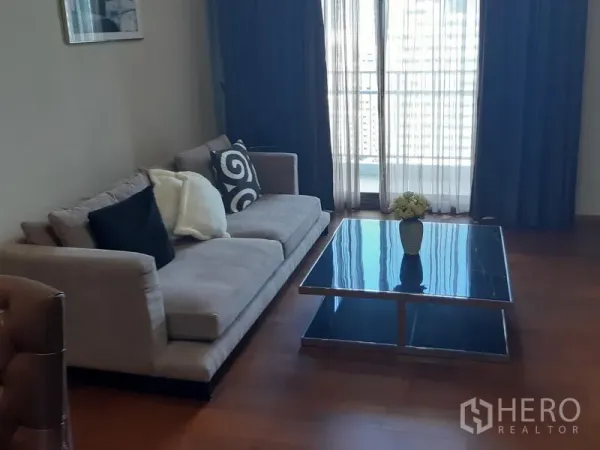 公寓 出租在Watthana, Bangkok - 客厅配沙发、玻璃茶几及通向阳台的落地窗帘。