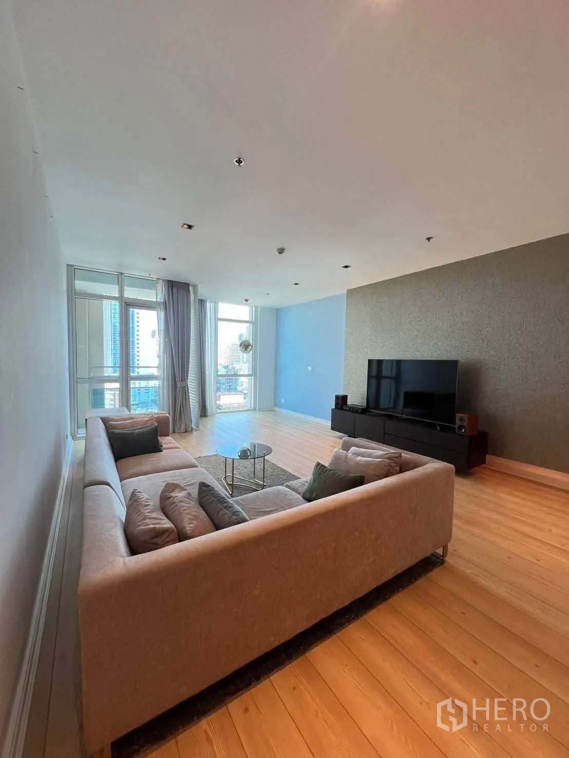 คอนโด for rent in Pathum Wan, Bangkok - ห้องนั่งเล่นกว้างพร้อมโซฟาตัวยาว ชั้นวางทีวี และหน้าต่างบานใหญ่