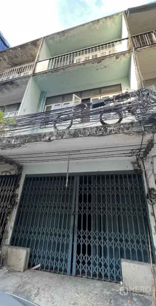 Shophouse for rent in Watthana, Bangkok - Street-facing multi-storey shophouse exterior in Watthana, Bangkok, with balconies, weathered facade and overhead utility cables near BTS Phra Khanong.
