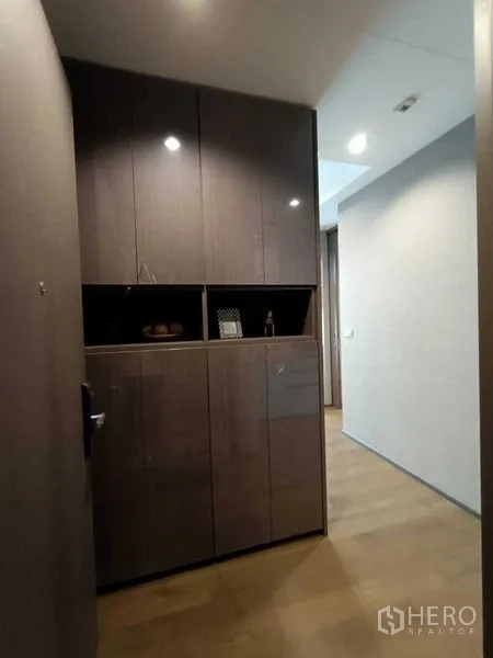 Condominium for rent or sale in Bang Rak, Bangkok - Entry foyer with floor-to-ceiling glossy cabinets and wood flooring in a modern condo.