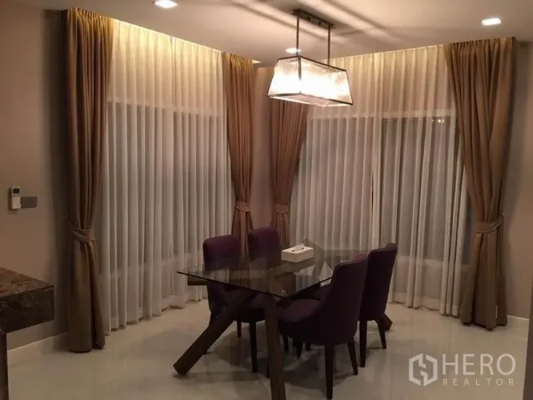 Detached House for rent or sale in Khlong Toei, Bangkok - Elegant dining area with glass table, purple chairs, and layered curtains under a pendant light.