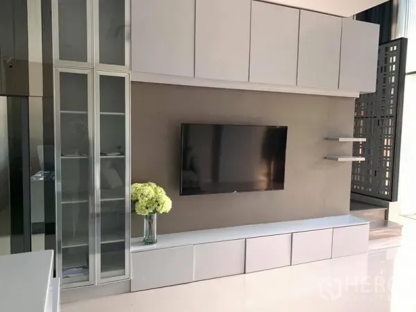 Home Office for rent - Modern living wall with built-in cabinets, TV, glass display and side shelves by the stairs.