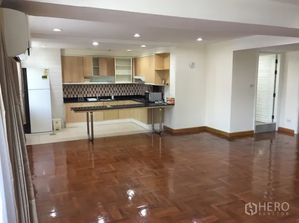 Condominium for rent in Watthana, Bangkok - Open-plan living area with polished parquet floors and a modern built-in kitchen.