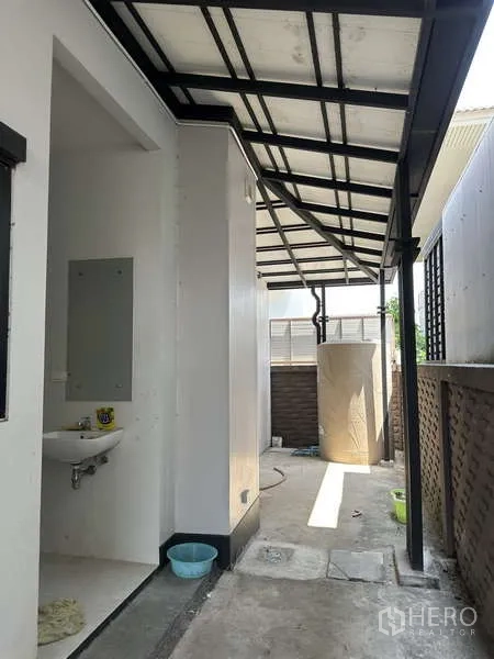 Detached House for sale in Lam Luk Ka, Pathum Thani - Covered utility area with outdoor sink and water tank.