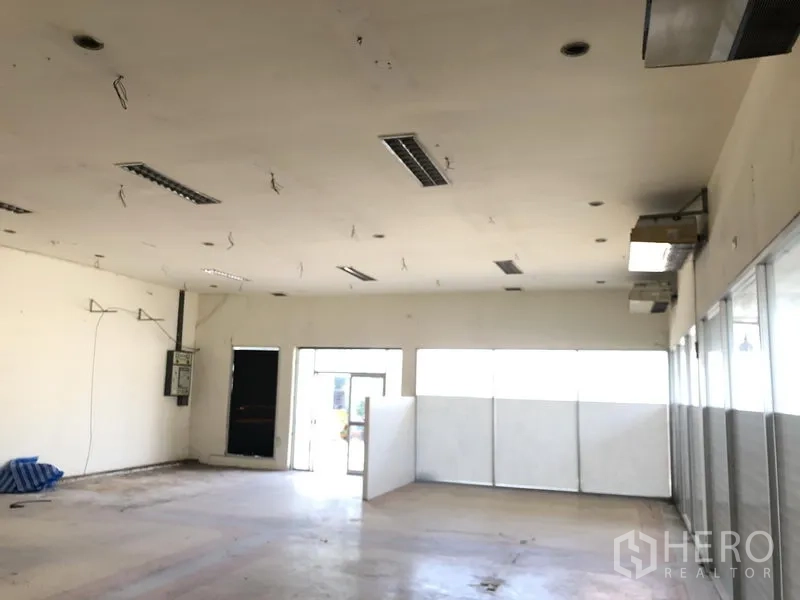 Warehouse for rent or sale in Lam Luk Ka, Pathum Thani - Open showroom or office hall with air-conditioning units and glass walls.