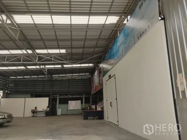 Warehouse for rent in Bueng Kum, Bangkok - Spacious steel-frame warehouse interior in Bueng Kum with high ceiling, skylights, concrete floor and a partitioned office or cold-room door.