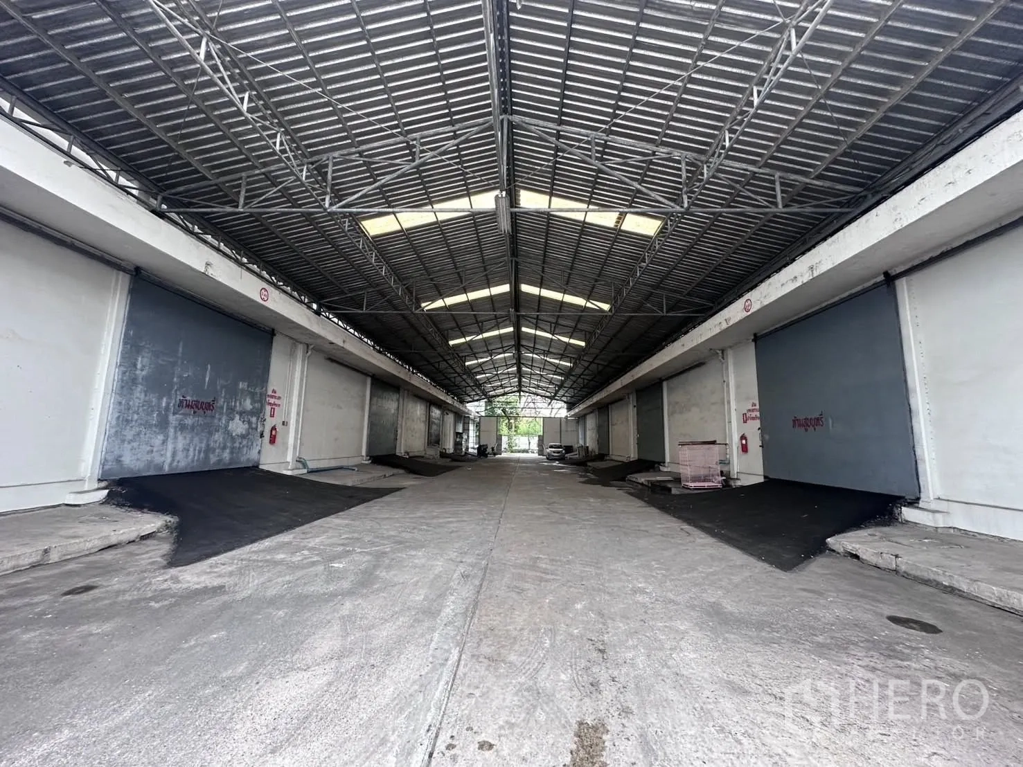 Warehouse for rent in Mueang Samut Prakan, Samut Prakan - Long covered loading area featuring several ramps and roller doors beneath a metal roof.