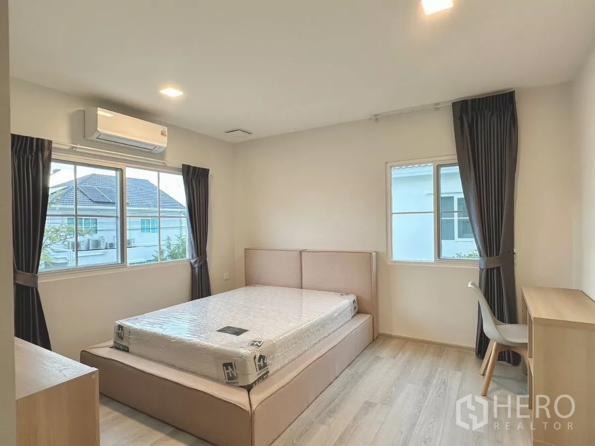 Detached House for rent in Bang Phli, Samut Prakan - Bright guest bedroom with bed by windows and wall-mounted air conditioner.