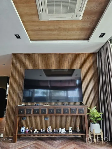 独立式住宅 出售在Thawi Watthana, Bangkok - 木质竖条特色墙，大屏电视与下沉天花。