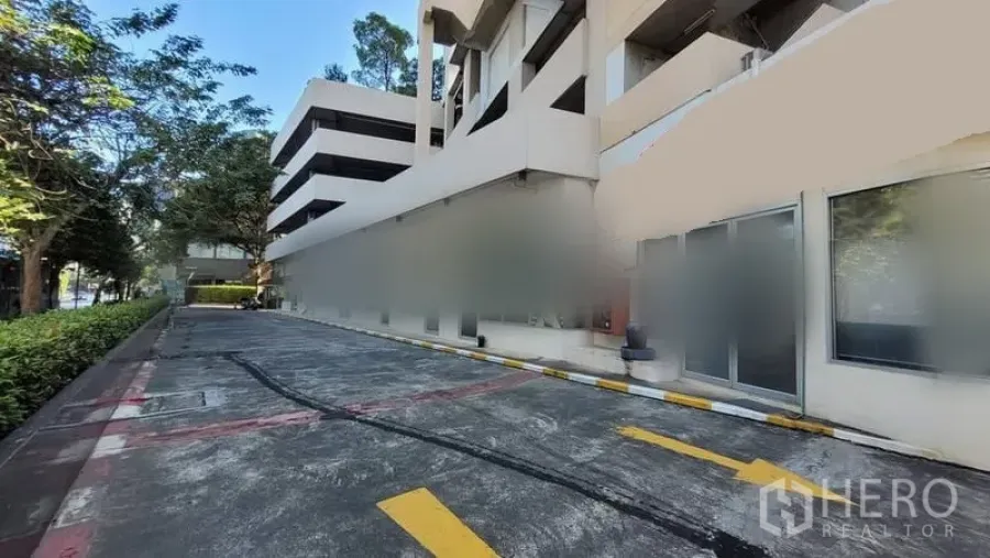 Retail Space for rent in Khlong Toei, Bangkok - Exterior of low-rise commercial building in Bang Na with driveway, greenery and ground-floor glass shopfronts.