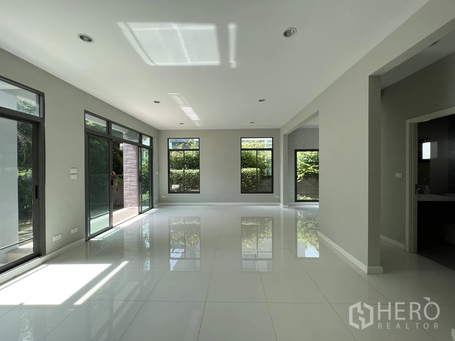 Detached House for sale in Suan Luang, Bangkok - Bright open-plan living area with large windows and glossy white tile floors.