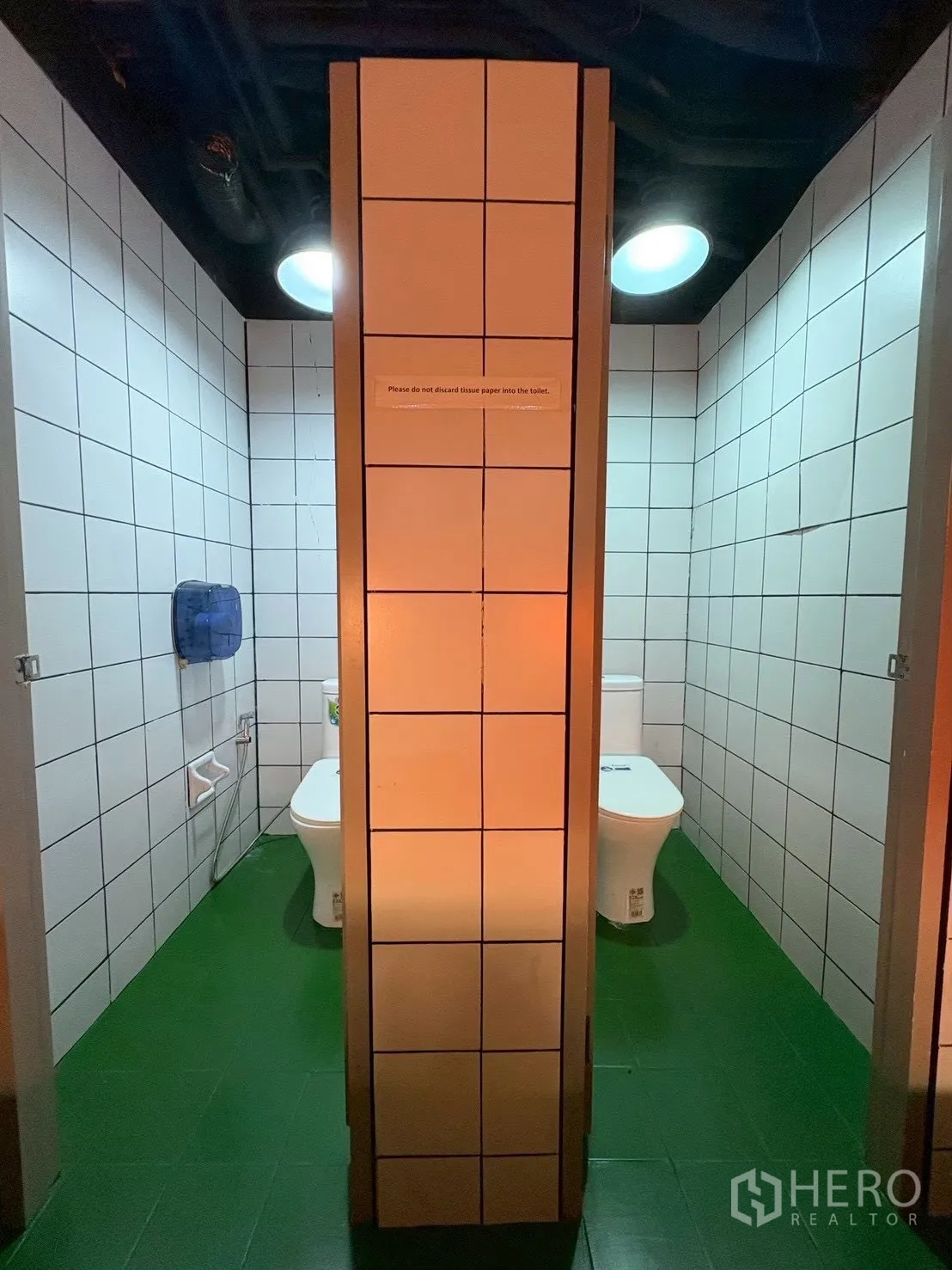Office Space for rent in Khlong Toei, Bangkok - Two toilet cubicles with white tiled walls and a green floor.