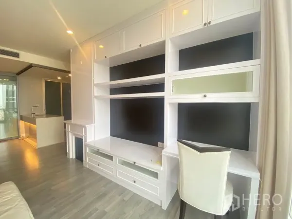Condominium for rent in Bang Rak, Bangkok - Living area with extensive built-in cabinetry facing the open kitchen and sliding glass doors.