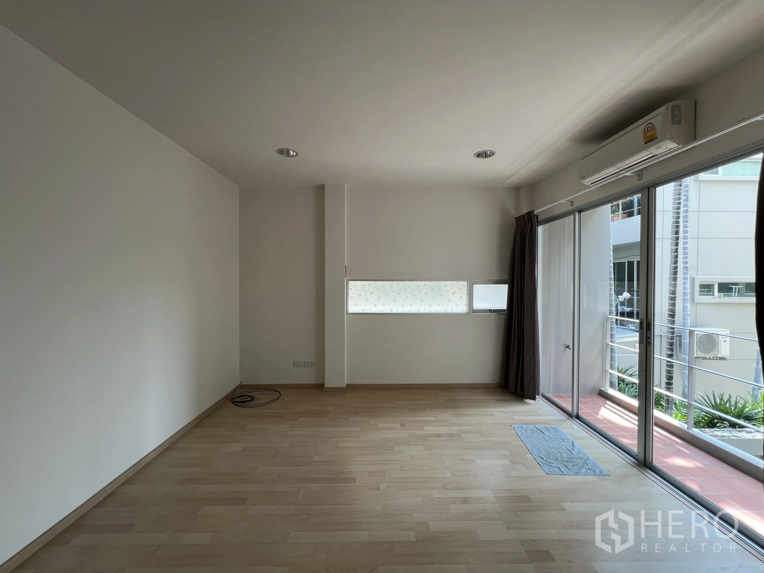 Townhouse for rent in Suan Luang, Bangkok - Bright upper floor room with balcony and curtains.