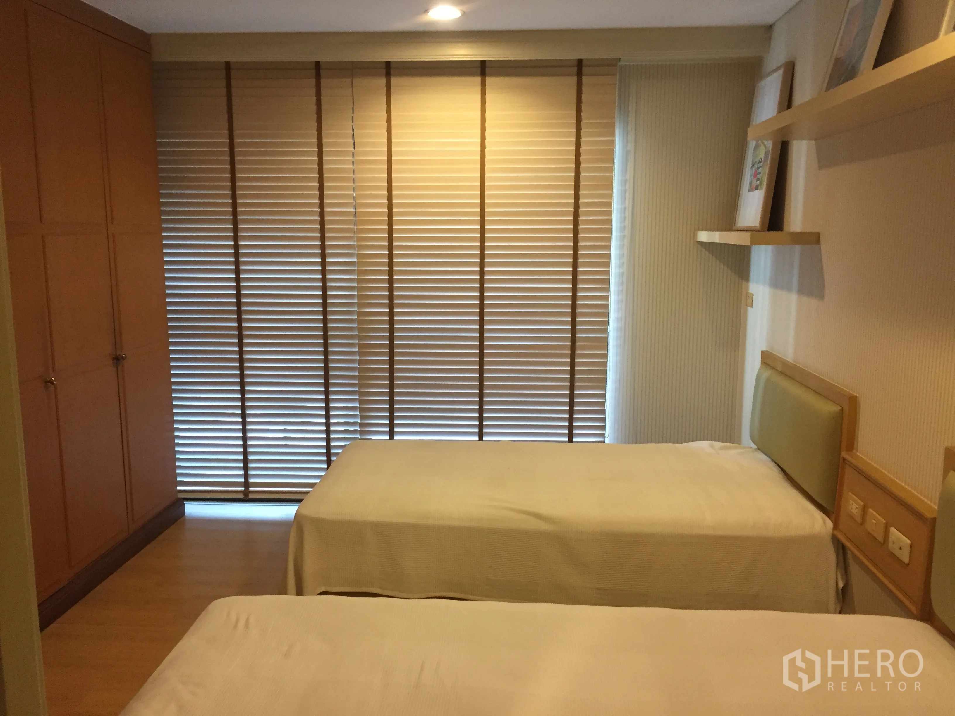 Condominium for rent in Pathum Wan, Bangkok - Bedroom with two single beds, built-in wardrobe, wood flooring, and full-height blinds.