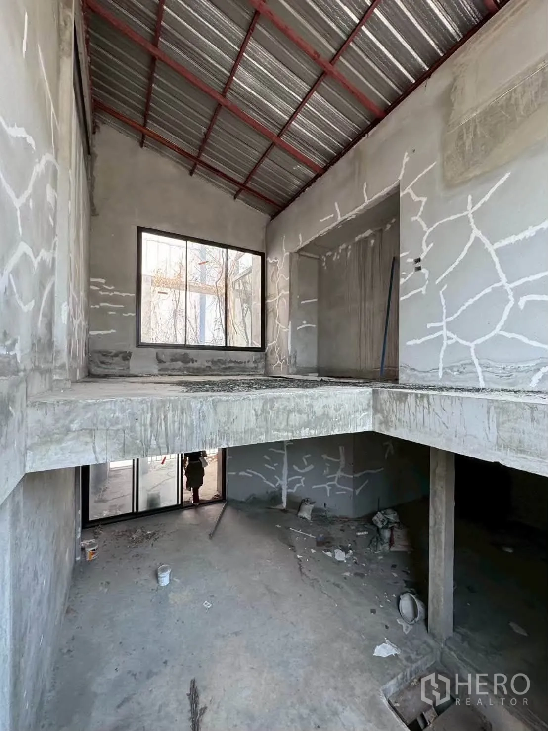 Shophouse for rent in Khlong Toei, Bangkok - Upper level with metal sheet roof, large window, and unfinished mezzanine floor.