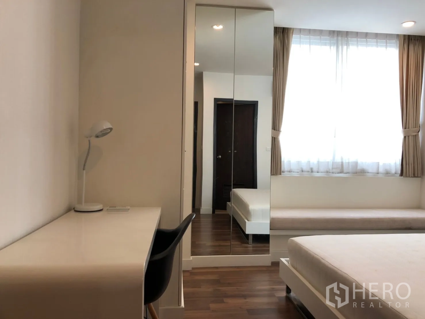 公寓 出租在Pathum Wan, Bangkok - 次卧带书桌、黑色椅子、镜面衣柜与明亮窗户。