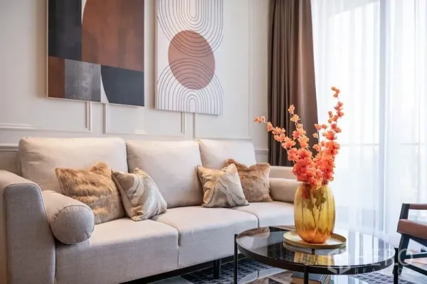 Condominium for rent in Khlong Toei, Bangkok - Neutral sofa with patterned cushions, geometric artwork and natural light from the balcony.
