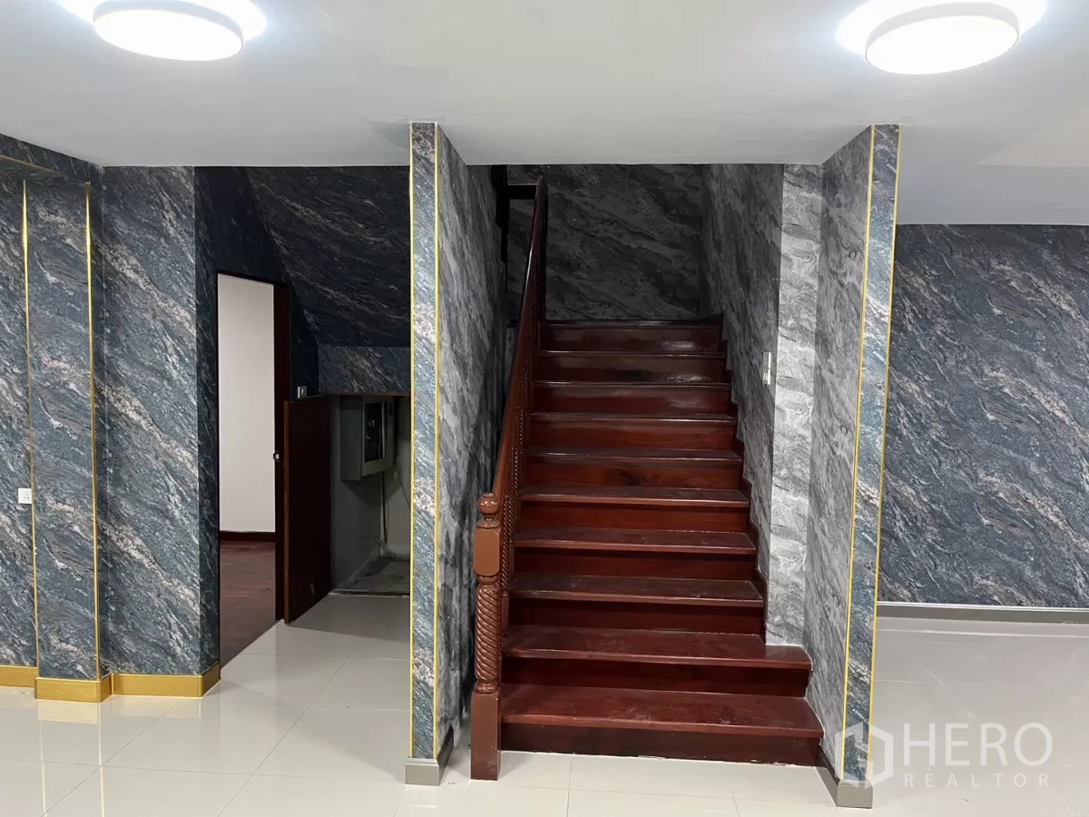 Detached House for rent in Watthana, Bangkok - Another view of the central hall highlighting the wooden staircase and tiled floors.