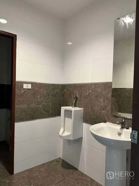 工厂 出租或出售在Bang Phli, Samut Prakan - 整洁的卫生间，墙面瓷砖、洗手盆与小便器。