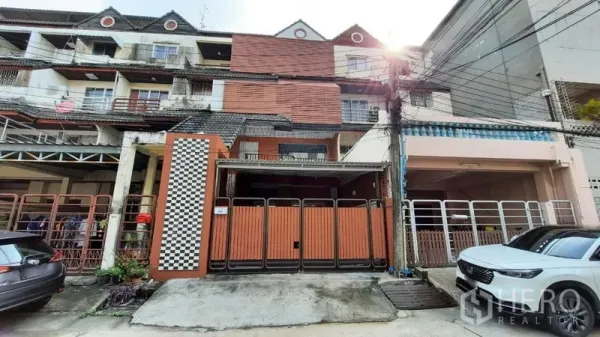 Townhouse for rent or sale in Suan Luang, Bangkok - Street-facing multi-level townhouse in Suan Luang, Bangkok with wooden gate and carport.