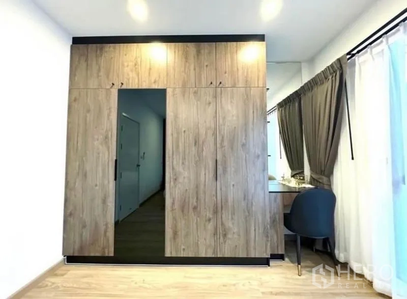Townhouse for rent - Floor-to-ceiling built-in wardrobe with wood finish and vanity beside the window.