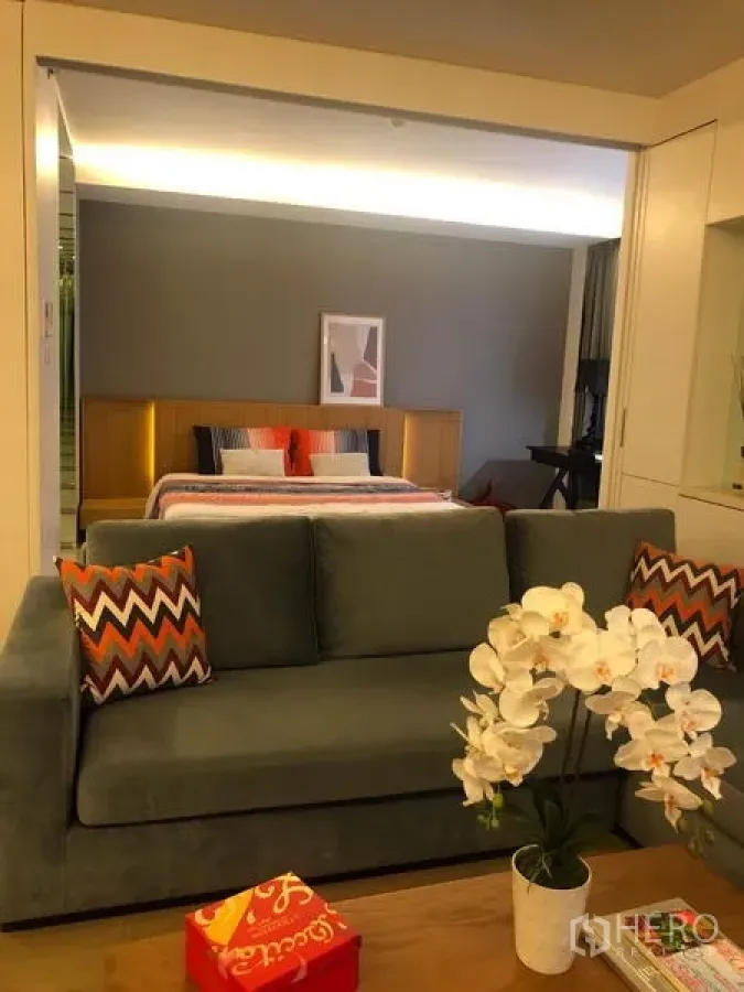 公寓 出租在Watthana, Bangkok - 温馨起居区，灰色沙发与茶几白色兰花，可望向卧室的开阔视野