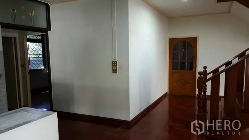 Detached House for rent in Khlong Toei, Bangkok - Hallway beside a wooden staircase and arched door with glossy timber flooring.