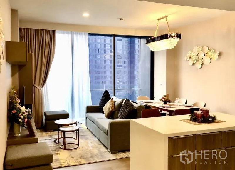 公寓 出租在Watthana, Bangkok - 客餐厅配水晶吊灯，推拉落地门通阳台与岛台操作区。