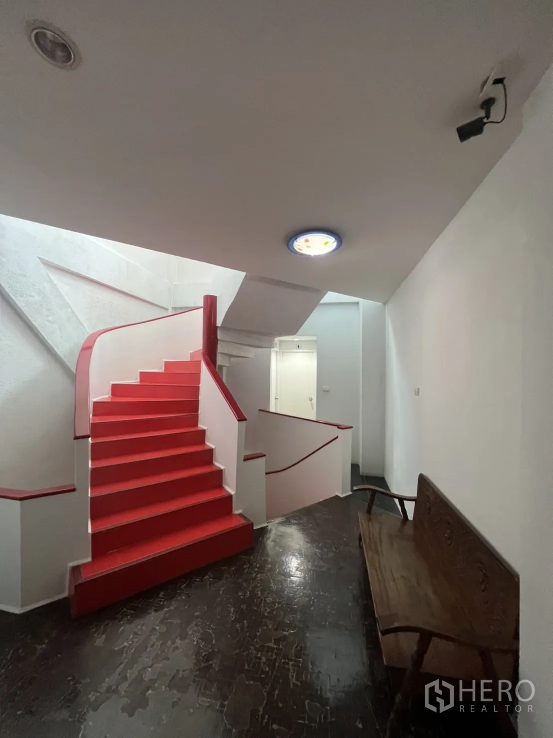 Shophouse for rent in Khlong Toei, Bangkok - Stair hall with bold red staircase, white walls and a security camera.