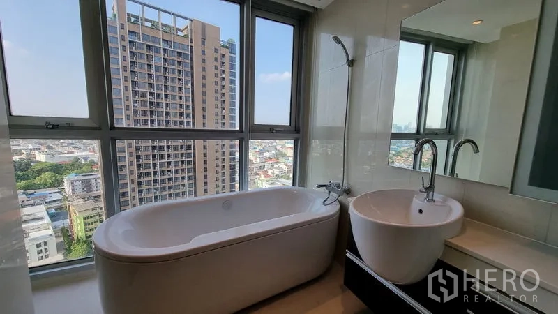 公寓 出售在Watthana, Bangkok - 浴室带浸泡浴缸与台盆，落地窗享城市景观。