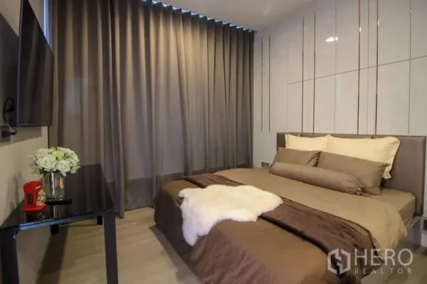 公寓 出售在Watthana, Bangkok - 卧室一角，遮光窗帘、壁挂电视与精致边几。