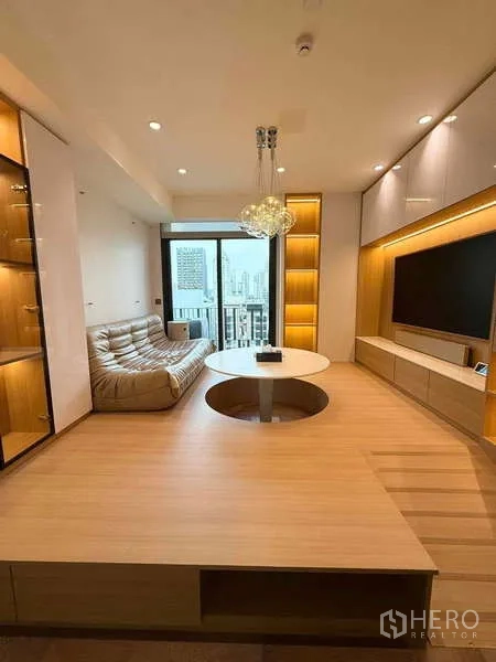 Condominium for rent in Watthana, Bangkok - Warm wood-accented living room with built-in TV wall, chandelier lighting, and balcony city view.