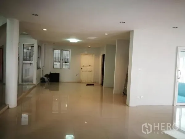 Detached House for rent in Phra Khanong, Bangkok - Spacious open-plan living area with glossy tile flooring, white walls, recessed lighting, and windows.