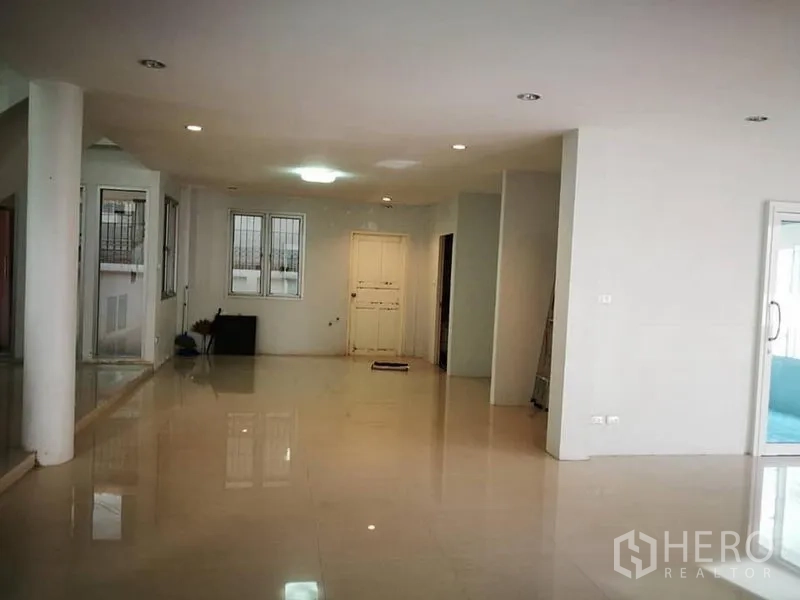 Detached House for rent in Phra Khanong, Bangkok - Spacious open-plan living area with glossy tile flooring, white walls, recessed lighting, and windows.