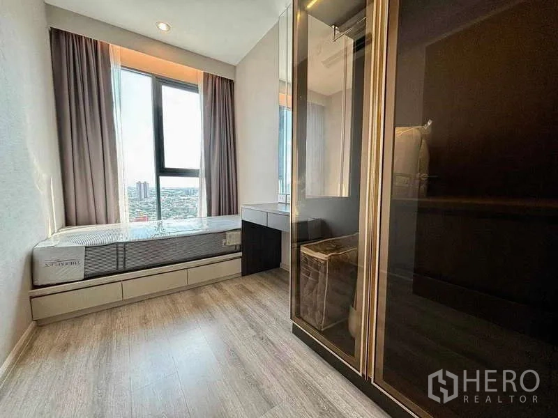 Condominium for rent or sale in Bang Na, Bangkok - Compact second bedroom with single bed, glass-door wardrobe and large window overlooking the city.